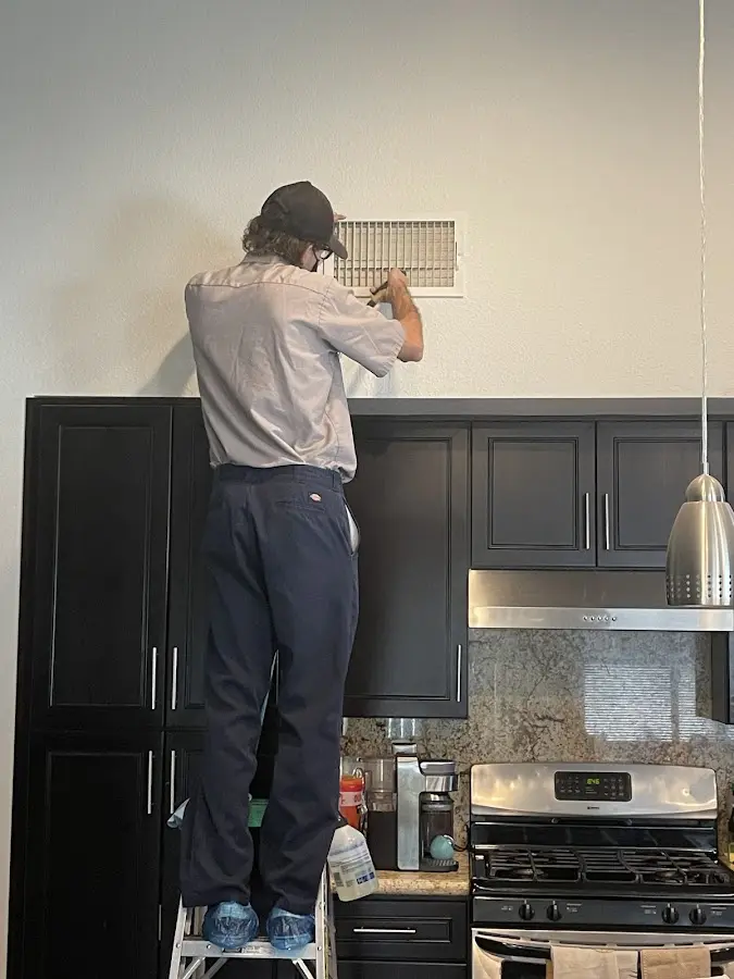 Technician inspecting an air vent during HVAC service in Saginaw